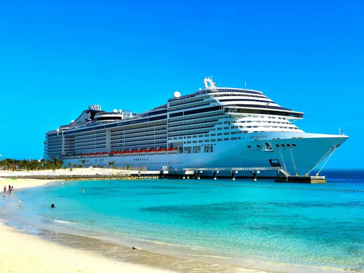 Large modern cruise ship docked at a tropical port with turquoise water